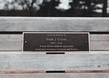 Ahşap bank üzerine yerleştirilmiş, 'In loving memory of' yazılı bronz anma plaketi.