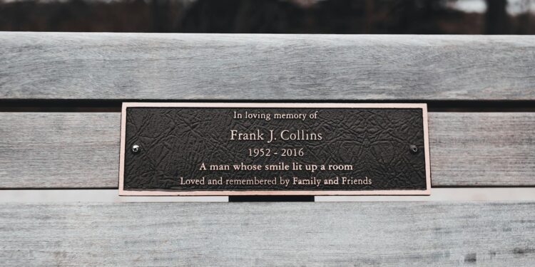 Ahşap bank üzerine yerleştirilmiş, 'In loving memory of' yazılı bronz anma plaketi.