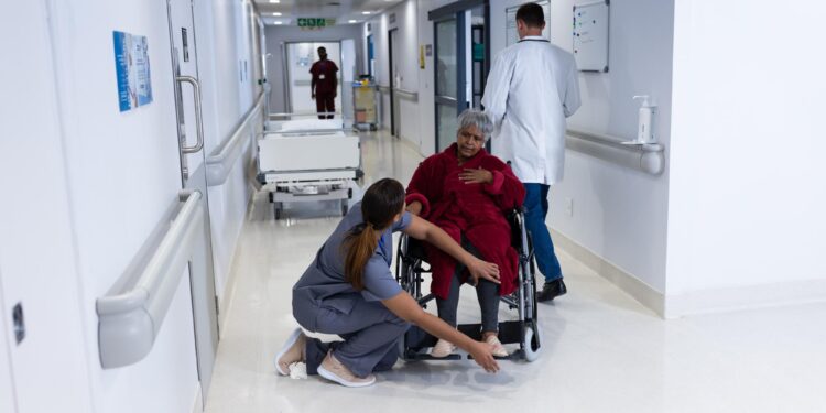 Hastane koridorunda yürüyen doktorlar ve tekerlekli sandalyedeki hasta.