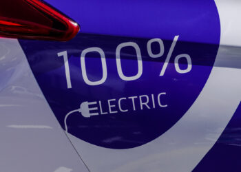 Mavi renkli elektrikli araç şarj yüzeyi üzerinde yüz yüzde elektrik yazısı.