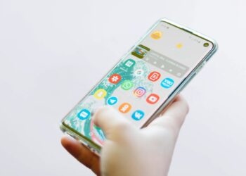 Şeffaf kılıflı bir akıllı telefon tutan kişinin ekranındaki uygulama simgeleri.