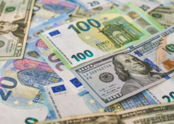 Karışık olarak masada duran 100 dolarlık ve 100 euroluk banknotlar.