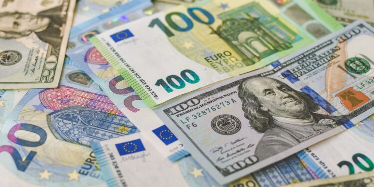 Karışık olarak masada duran 100 dolarlık ve 100 euroluk banknotlar.