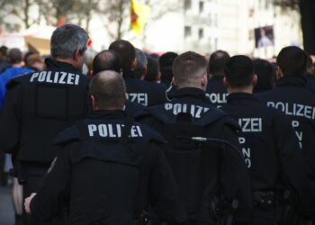 Sırtlarında POLİZE yazılı üniformalarla sokakta yürüyen polis memurları kalabalığı.