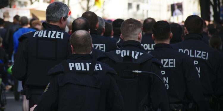 Sırtlarında POLİZE yazılı üniformalarla sokakta yürüyen polis memurları kalabalığı.