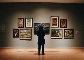 Sanat galerisinde duvardaki tablolara bakan tesettürlü bir ziyaretçi.