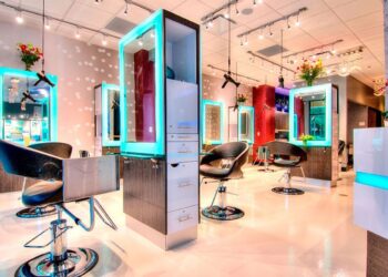 Aydınlık ve modern tasarımlı, kuaför koltukları ve aynaları bulunan boş bir salon.