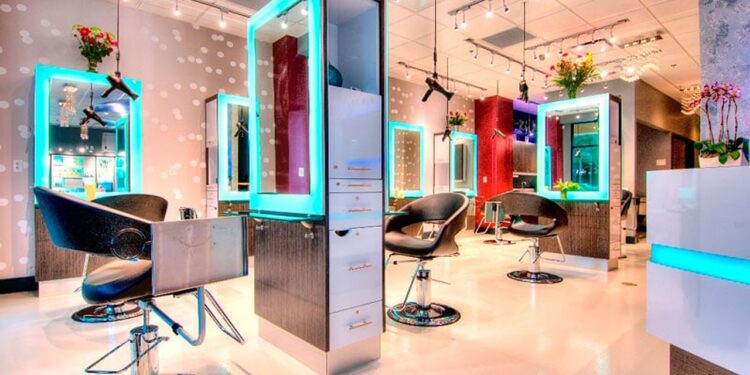 Aydınlık ve modern tasarımlı, kuaför koltukları ve aynaları bulunan boş bir salon.
