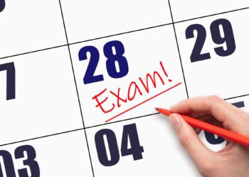Kırmızı kalemle bir takvim yaprağındaki tarihin üzerine 'Exam!' yazıldığı yakın plan fotoğrafı
