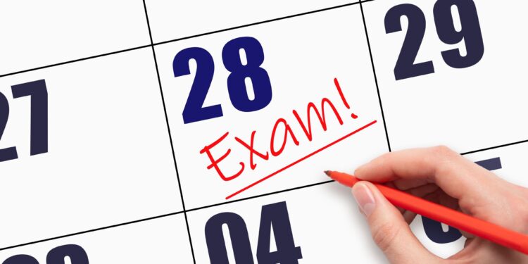 Kırmızı kalemle bir takvim yaprağındaki tarihin üzerine 'Exam!' yazıldığı yakın plan fotoğrafı