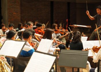 Şefin yönetiminde keman çalan müzisyenlerin yer aldığı orkestra provası
