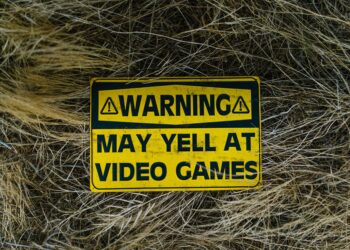 Kuru otlar arasında 'Warning' yazılı sarı renkli uyarı levhası.