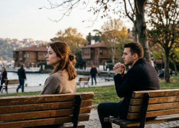 Boğaz manzaralı parkta iki ayrı bankta oturan düşünceli genç kadın ve erkek.