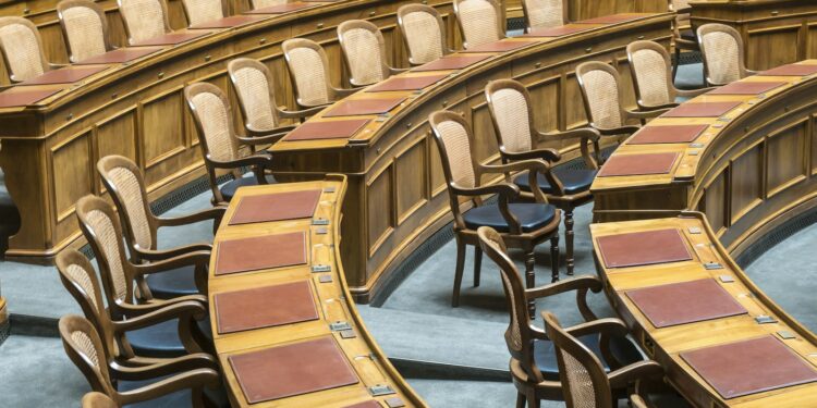 Ahşap kürsüleri ve deri detaylı sandalyeleriyle meclis genel kurul salonu.