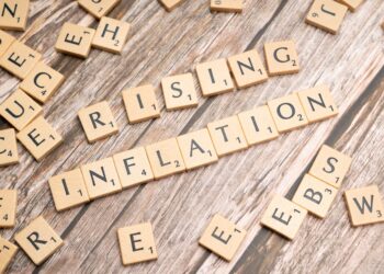 Ahşap harf karolarından oluşturulmuş 'RISING INFLATION' yazısı ve dağınık harfler.
