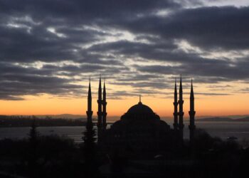 Gün batımında bulutlu gökyüzü altında İstanbul'un tarihi silueti ve minareleri görülüyor.